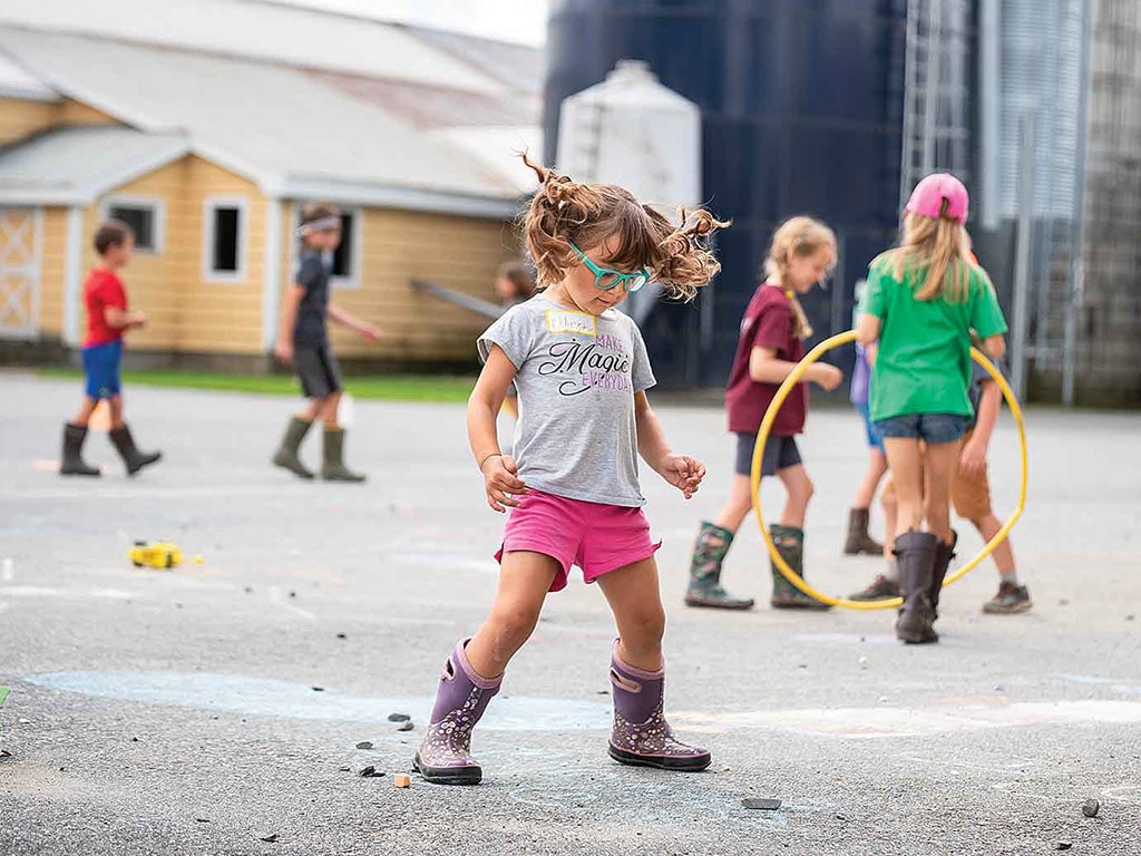 Children playing with barnyard in the background